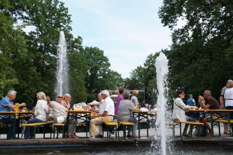 Personen sitzen an Biertischen am Fontänenhof